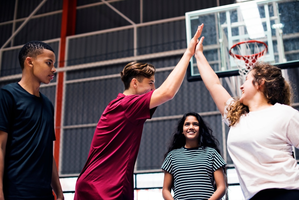 Teens celebrate on a basketball court.